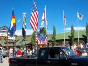 A thumb nail view of Grand Lake, Colorado during Constitution Week in September looking at a small black truck with several flags, with the town park sign and flags in the background; click here to open a window with a larger picture.
